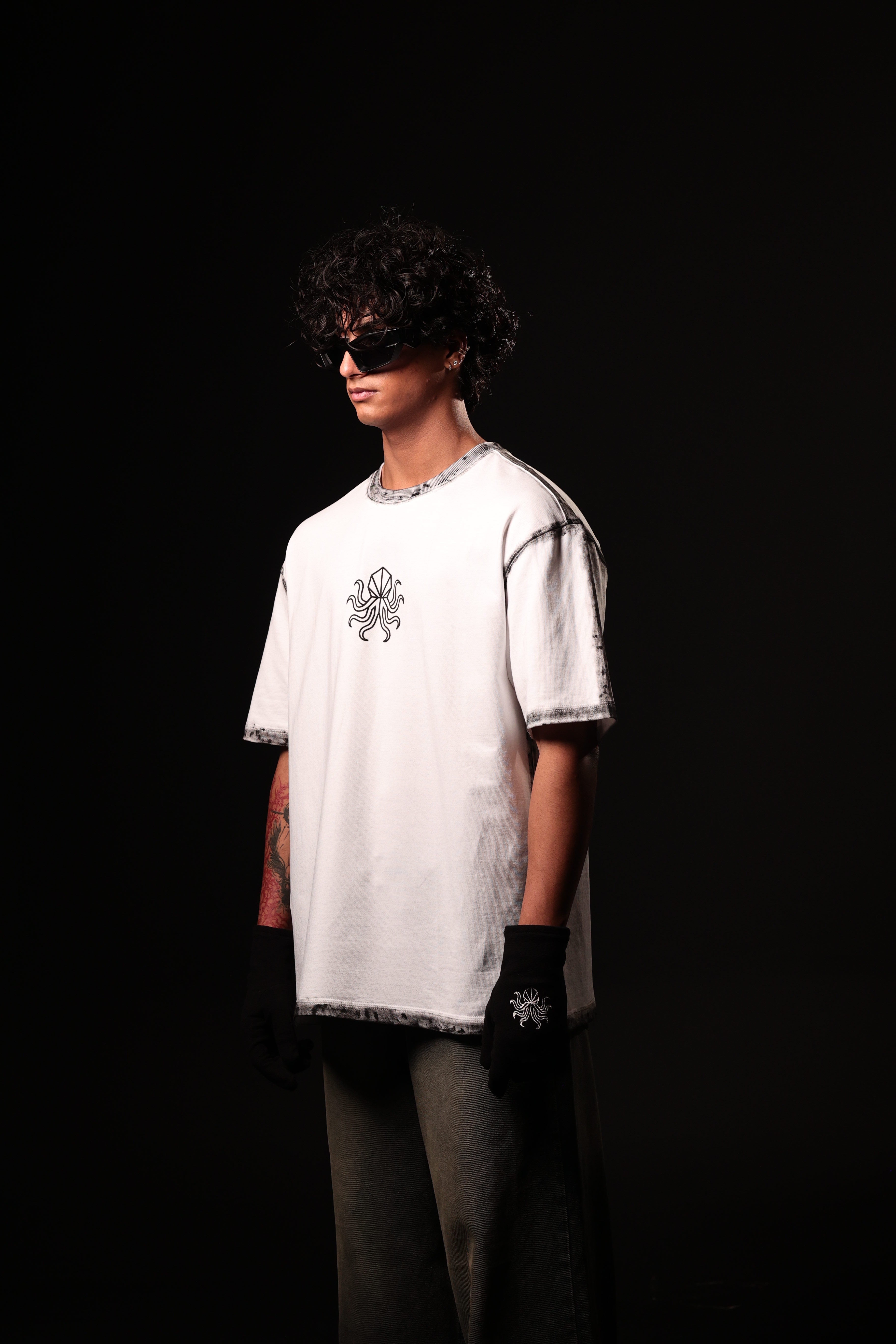 Person wearing a white oversized t-shirt with a design on a black background