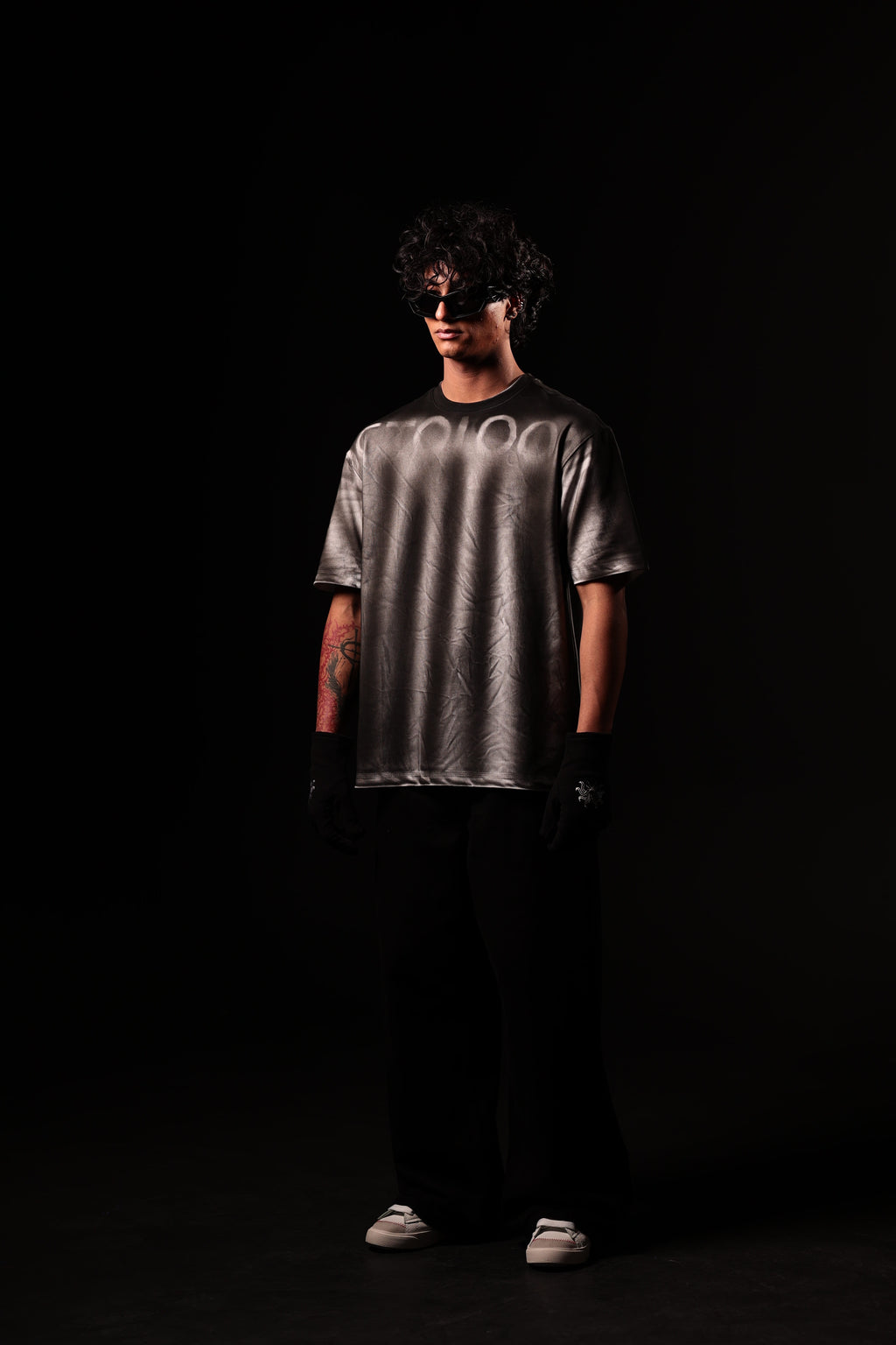 Person wearing a reflective silver t-shirt on a black background