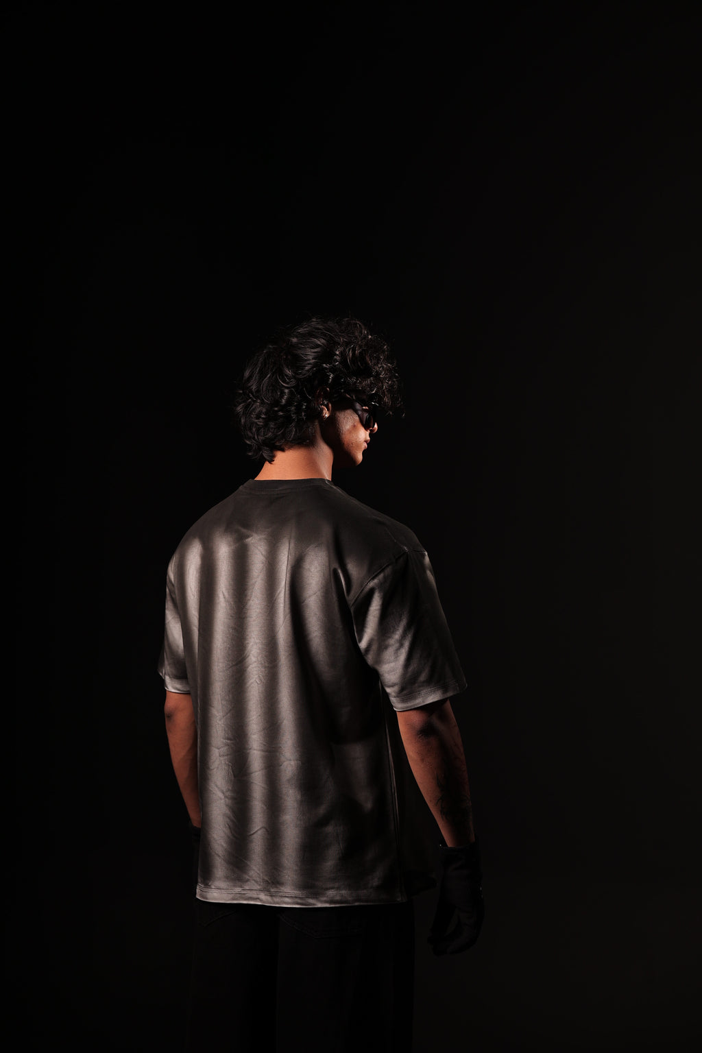 Person wearing a dark metallic shirt against a black background