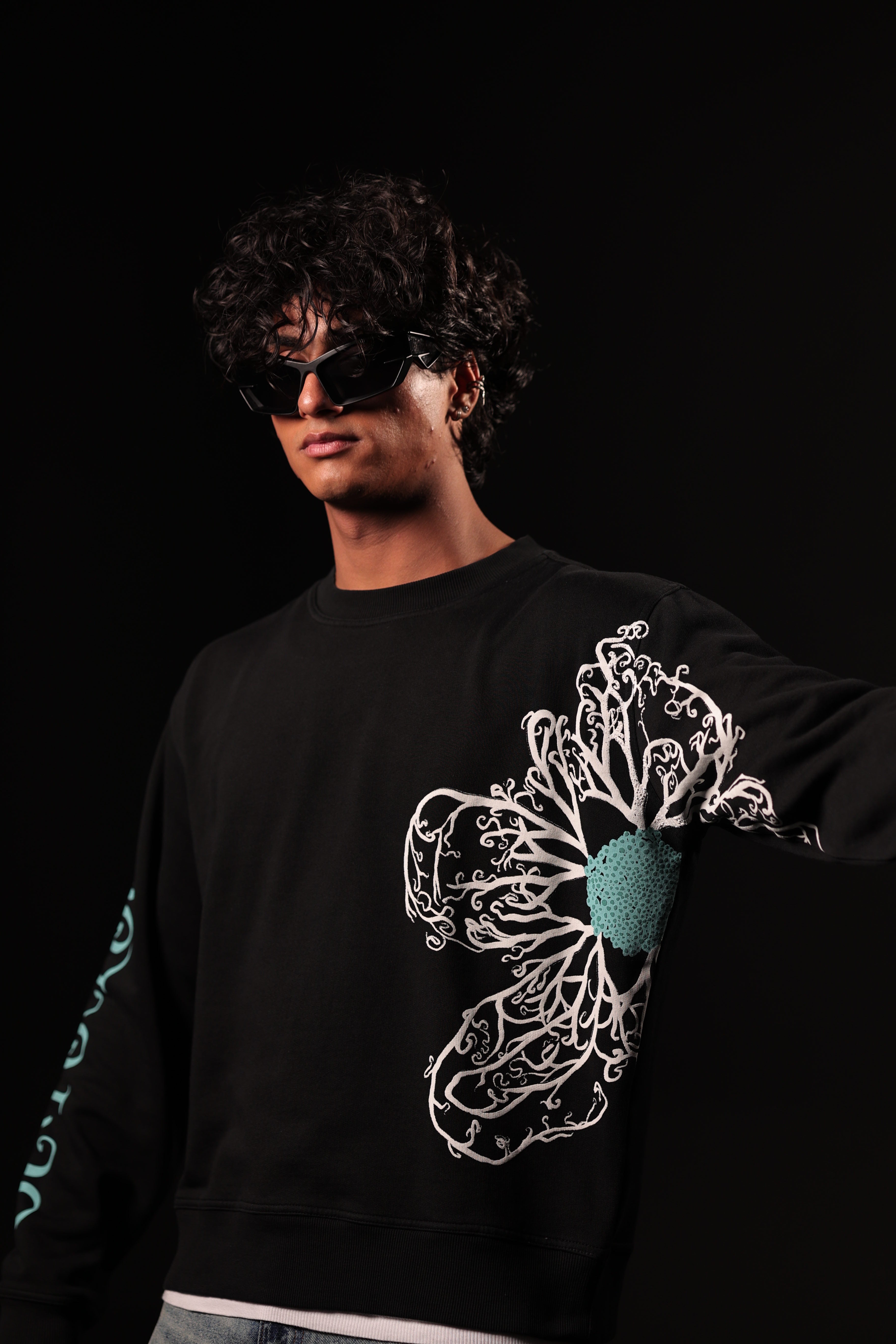 Person wearing a black sweatshirt with a floral design on a black background