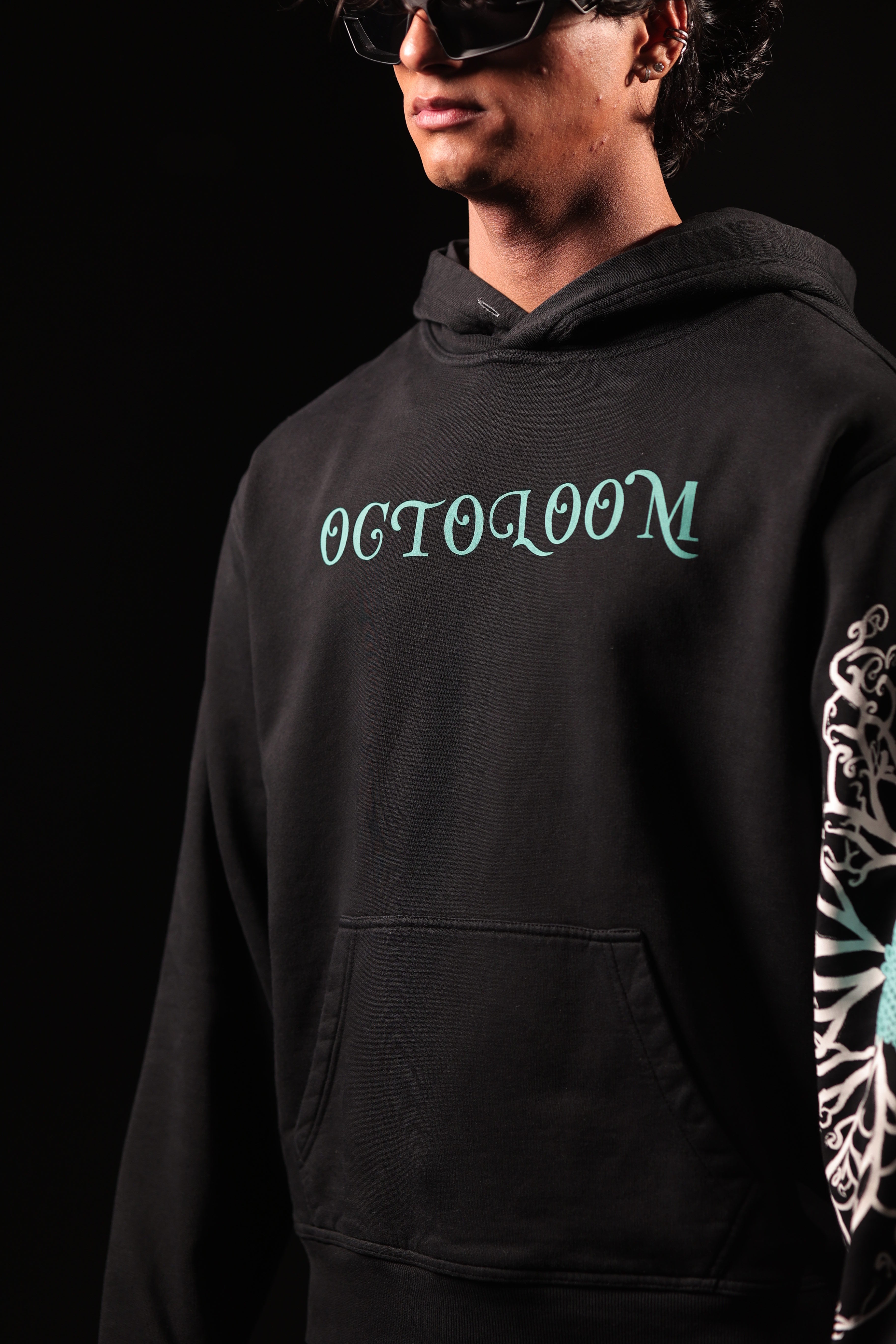 Person wearing a black hoodie with 'OCTOLOOM' text and a colorful sleeve design on a dark background
