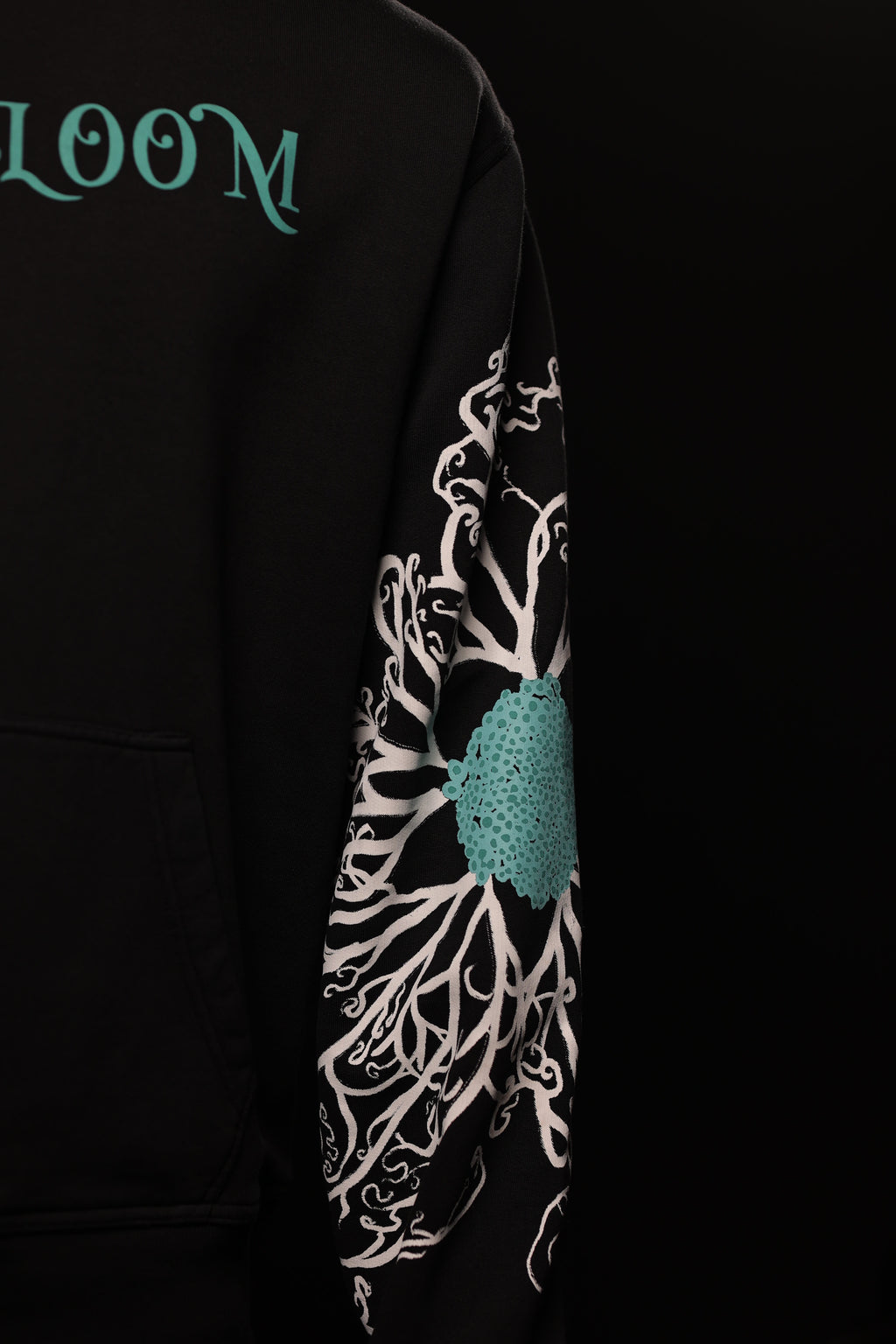 Black hoodie with floral design and 'LOOM' branding on sleeve against a black background