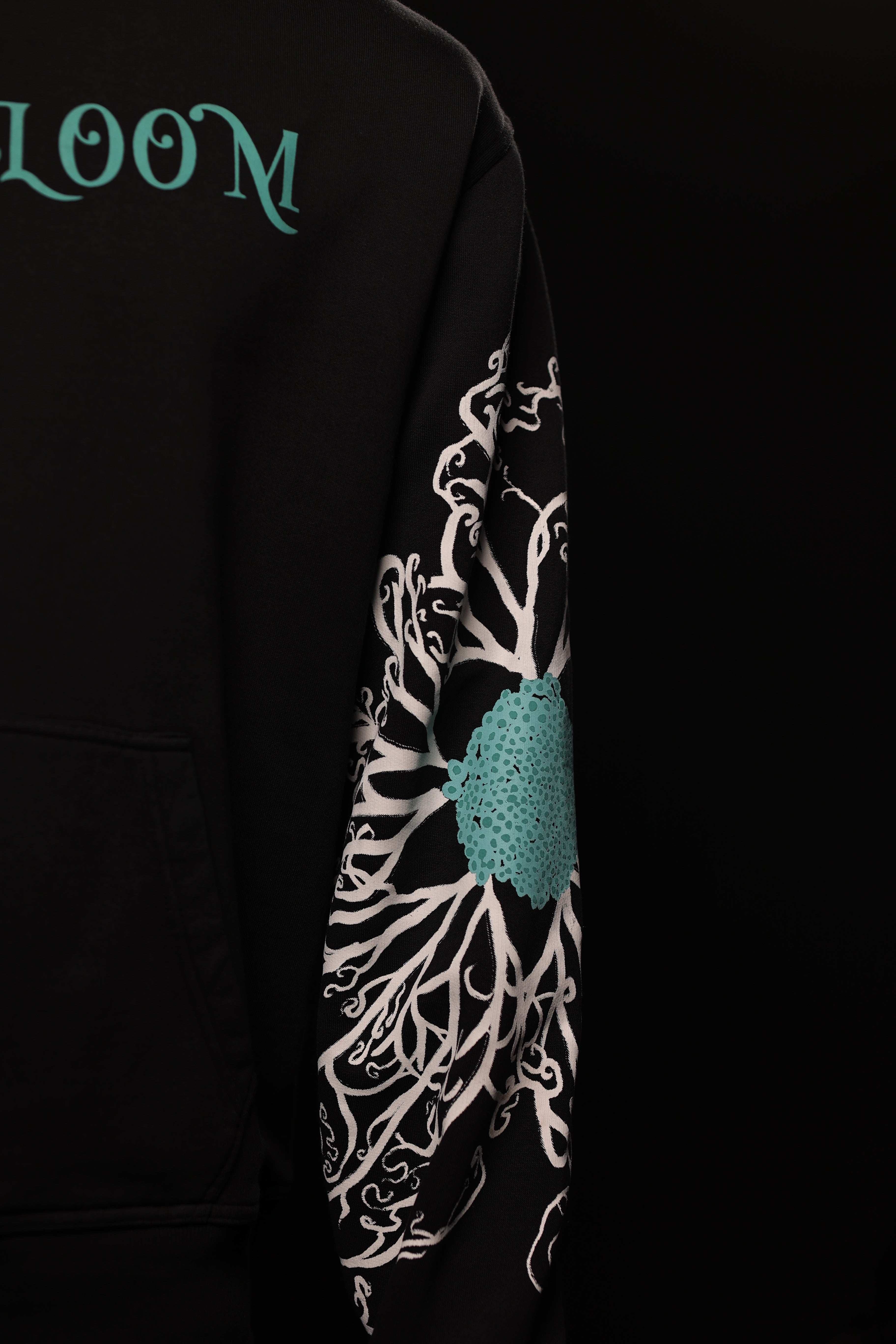Black hoodie with floral design and 'LOOM' branding on sleeve against a black background