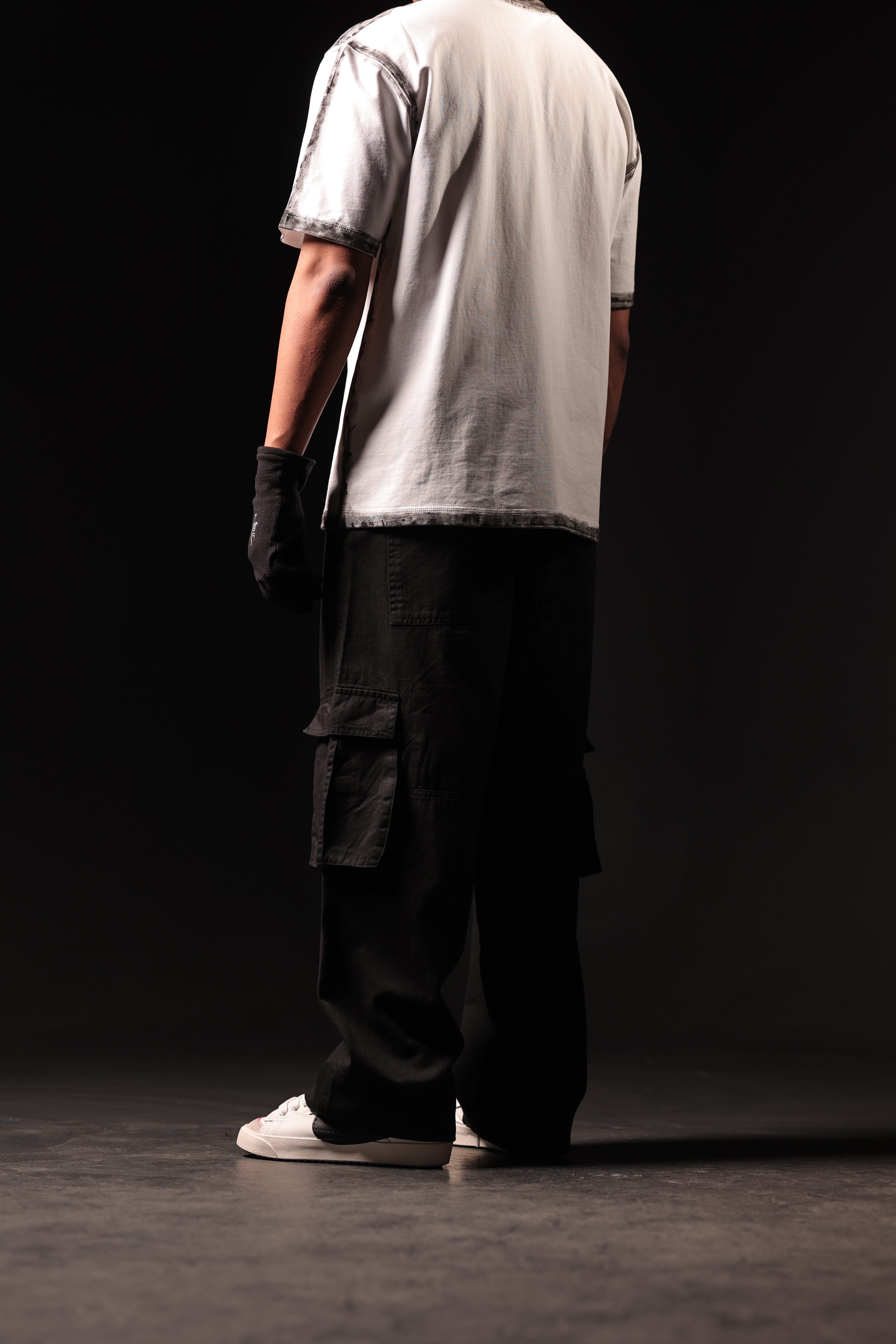 Person wearing a white shirt and dark pants on a black background