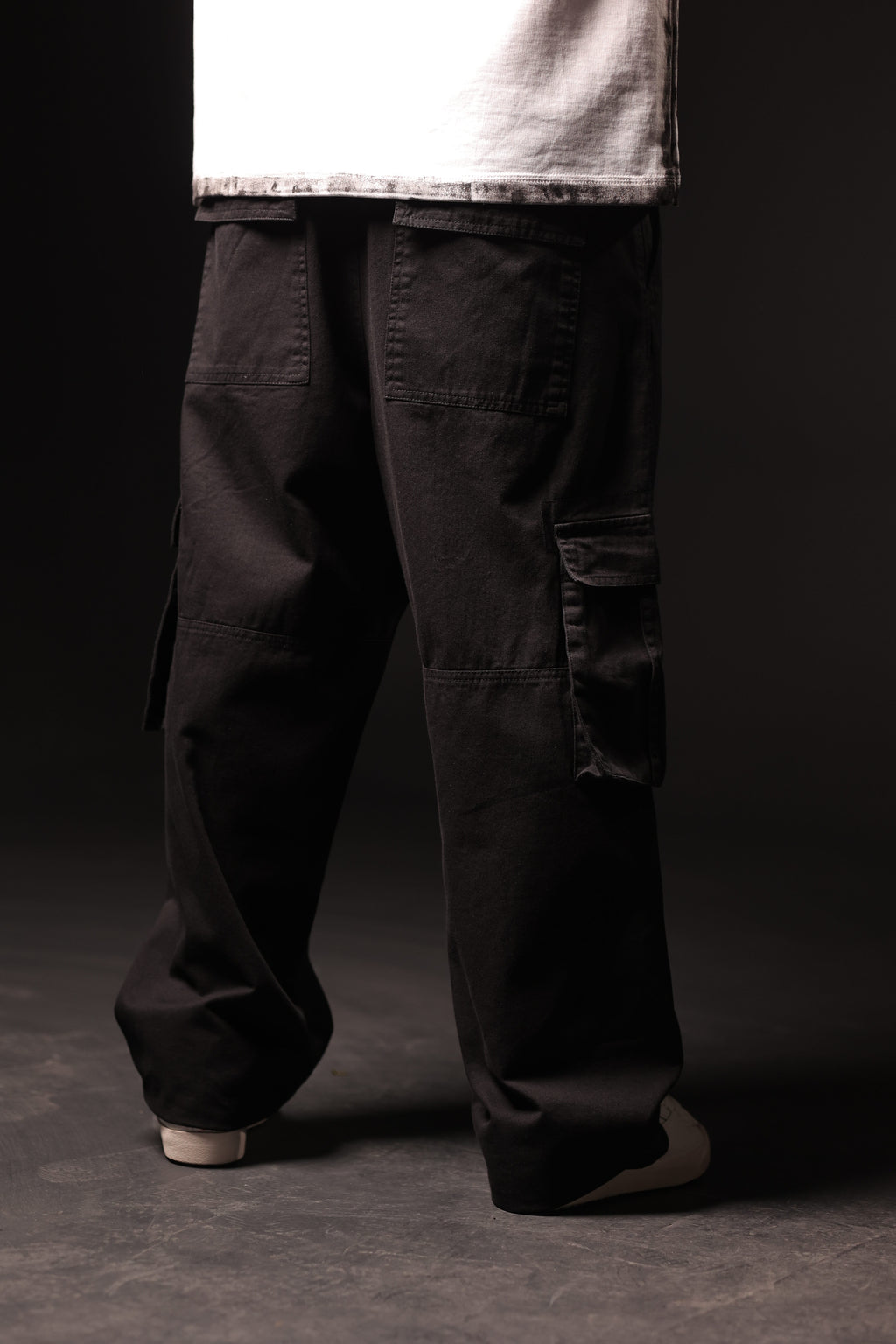 Person wearing black cargo pants on a dark background