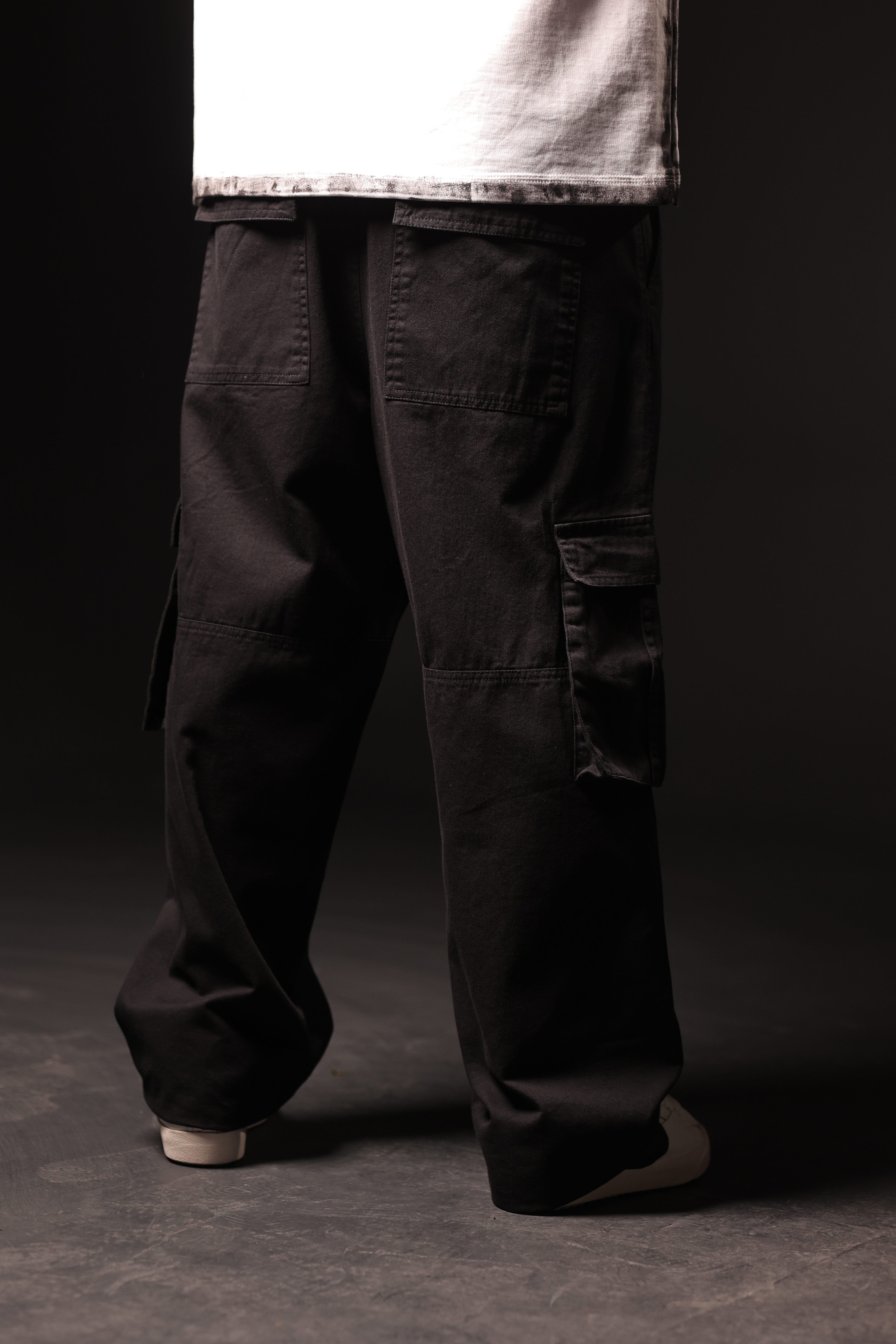 Person wearing black cargo pants on a dark background