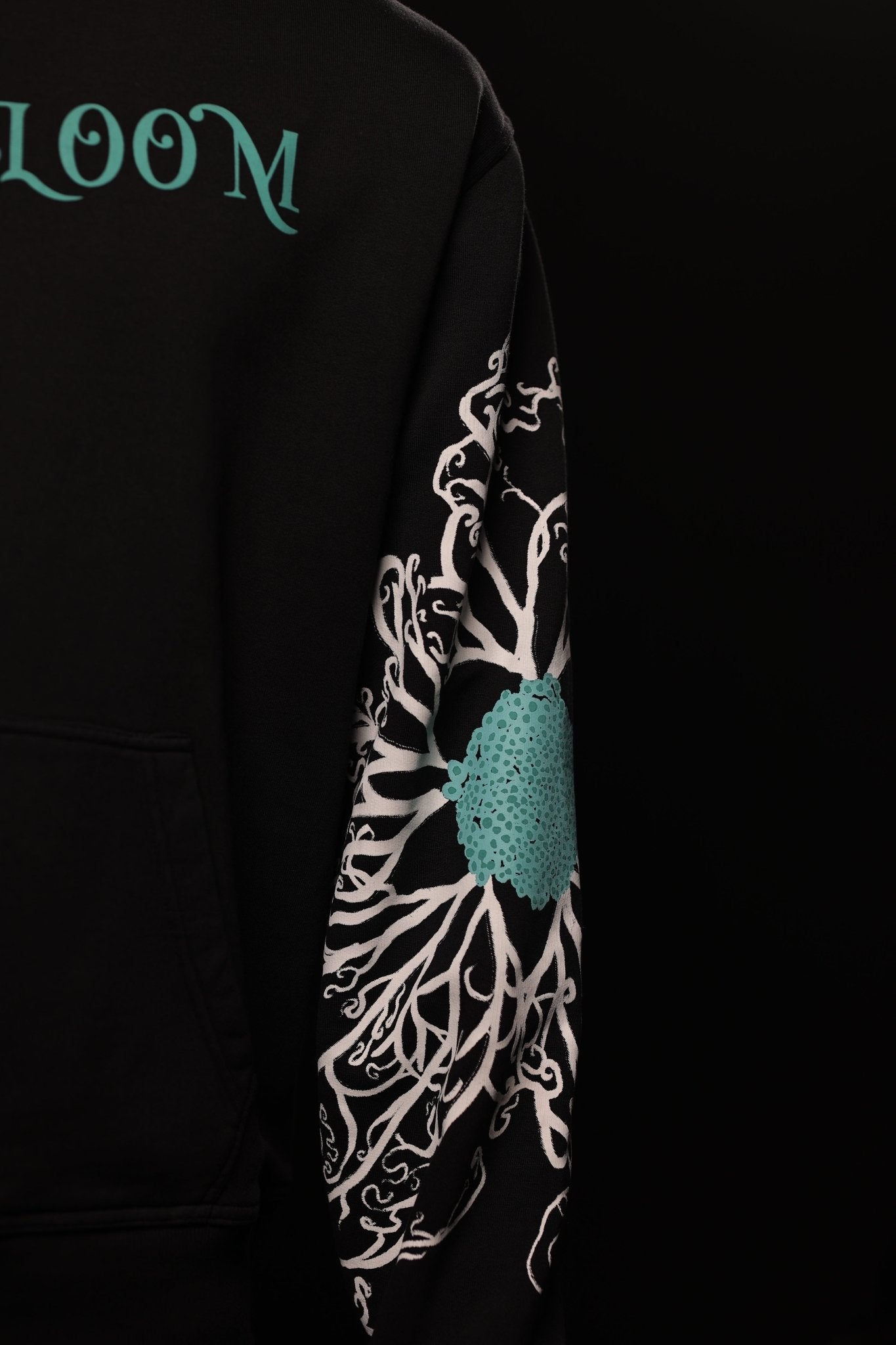 Black hoodie with floral design and 'LOOM' branding on sleeve against a black background