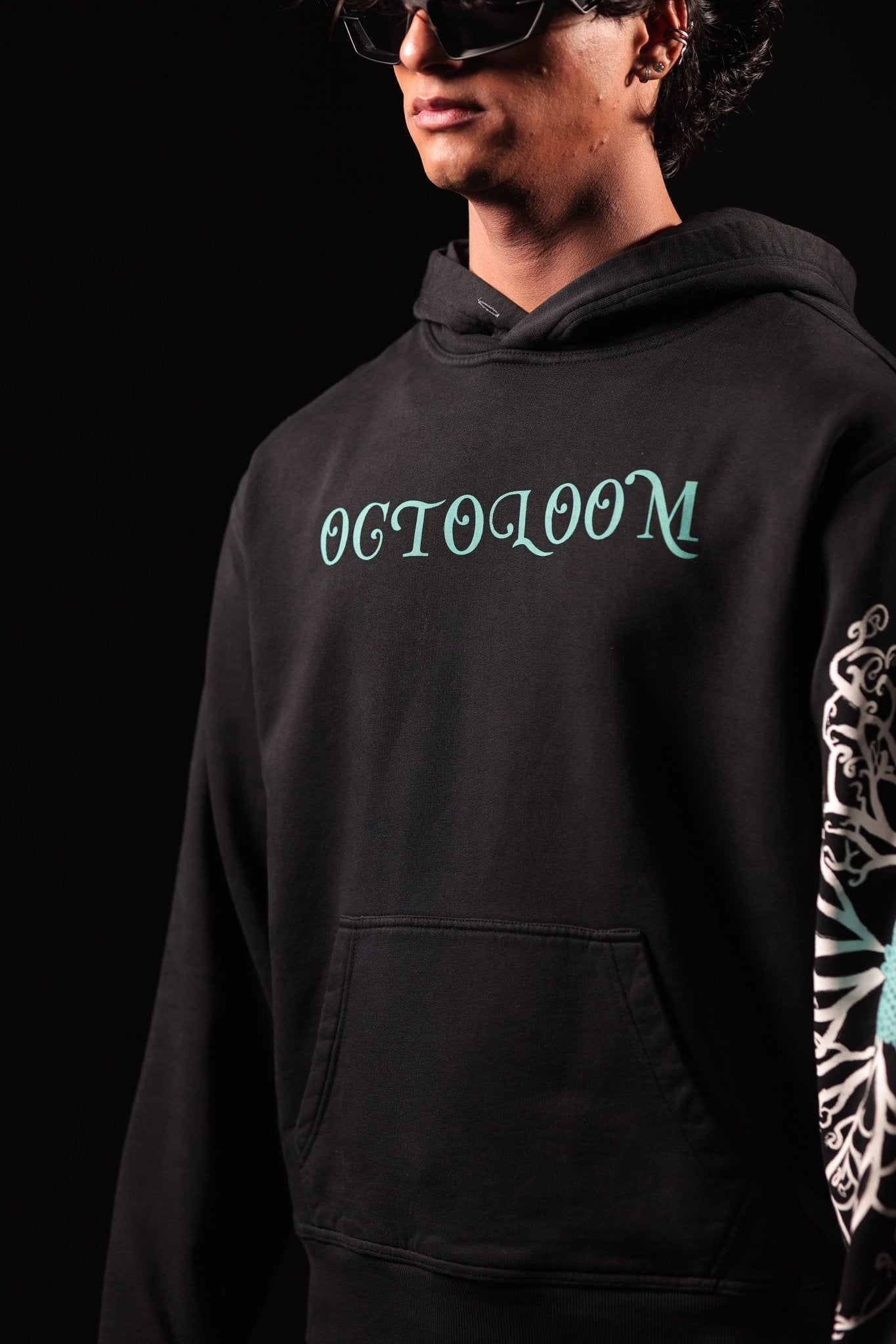 Person wearing a black hoodie with 'OCTOLOOM' text and a colorful sleeve design on a dark background