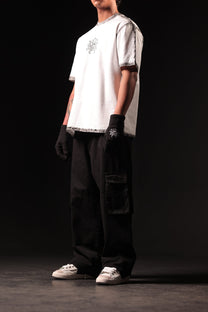Person wearing a white t-shirt, black gloves, and dark pants on a black background