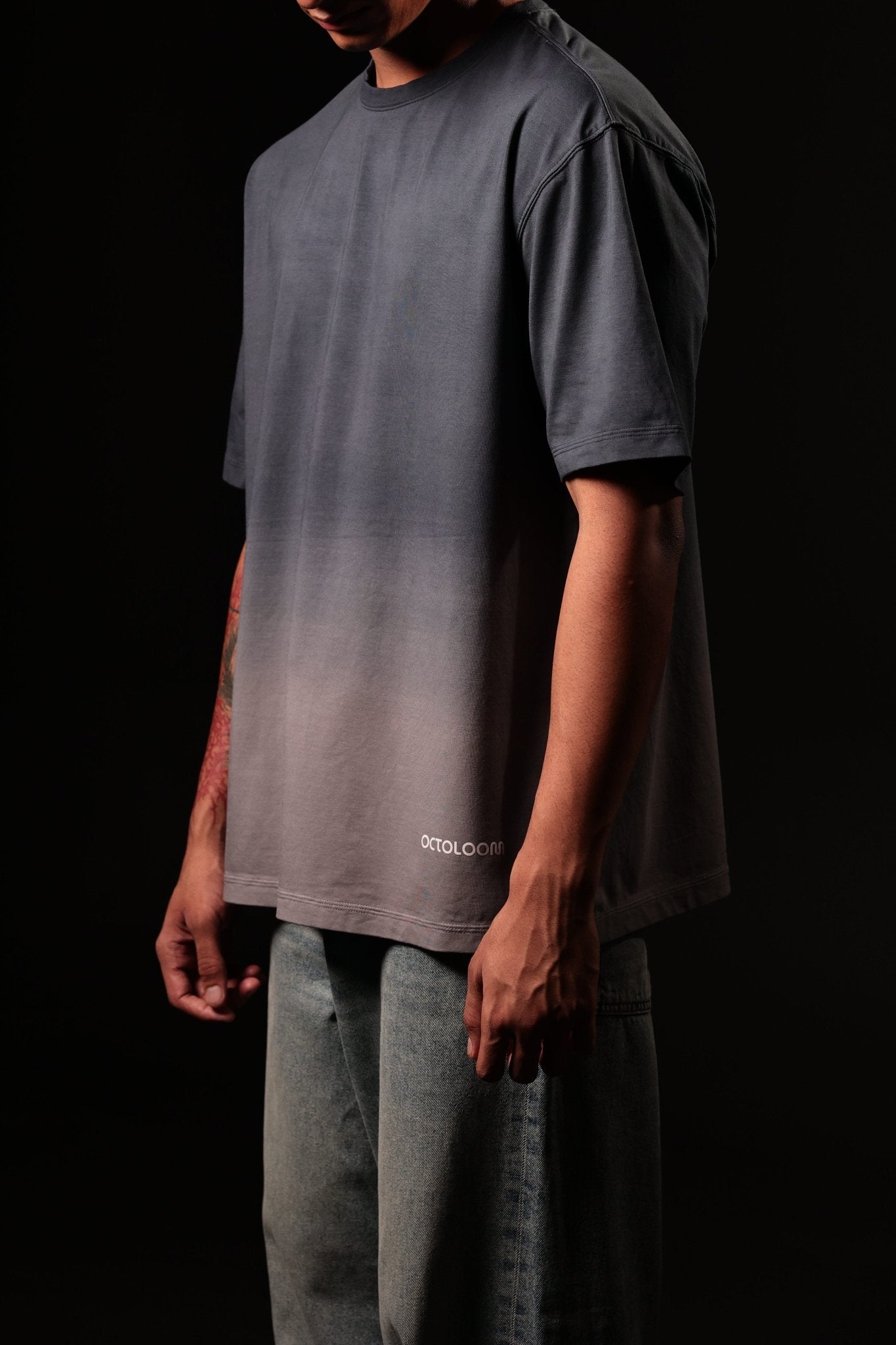 Person wearing a gray gradient t-shirt with 'Cotopaxi' branding on a black background