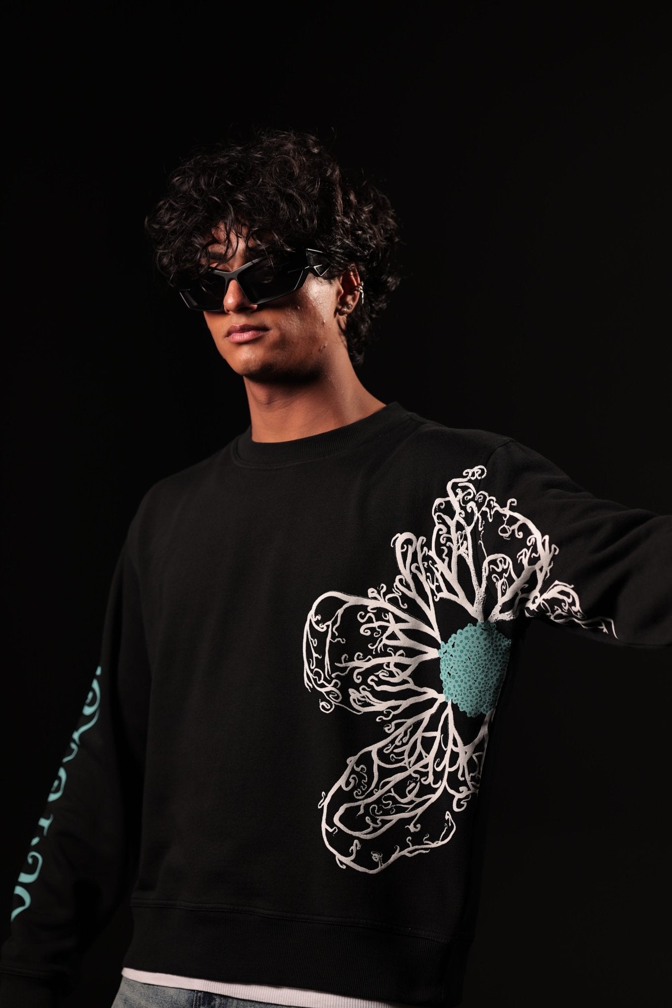 Person wearing a black sweatshirt with a floral design on a black background