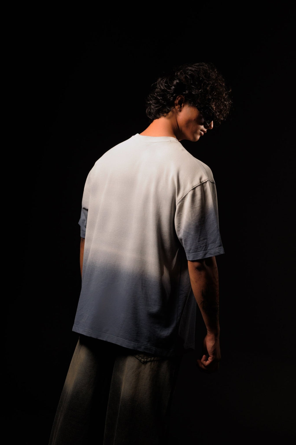 Person wearing a gradient t-shirt against a black background