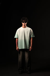 Person wearing a light green t-shirt and dark pants against a black background