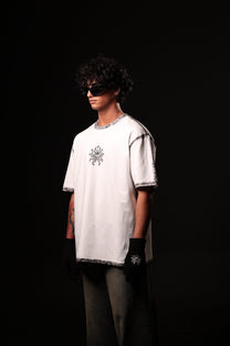 Person wearing a white oversized t-shirt with a design on a black background