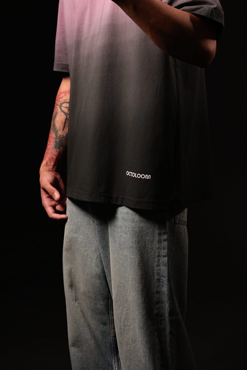 Person wearing a black t-shirt with 'octoloom' logo and light gray pants on a black background