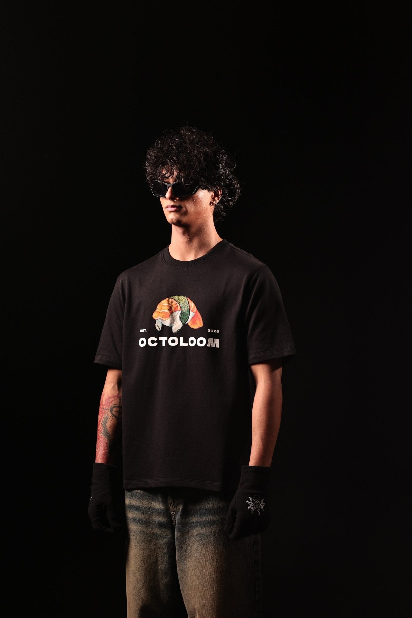 Person wearing a black t-shirt with a graphic design and text, standing against a black background